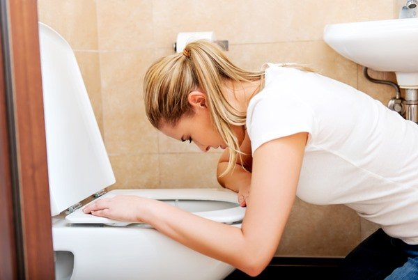Mulher em frente a um vaso sanitário como se fosse vomitar - Metrópoles