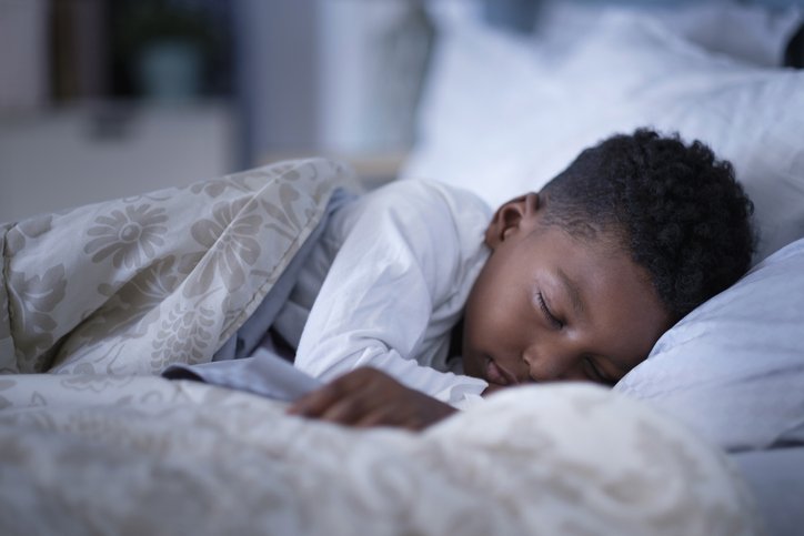 Criança dormindo em uma cama com lençol estampado - Metrópoles