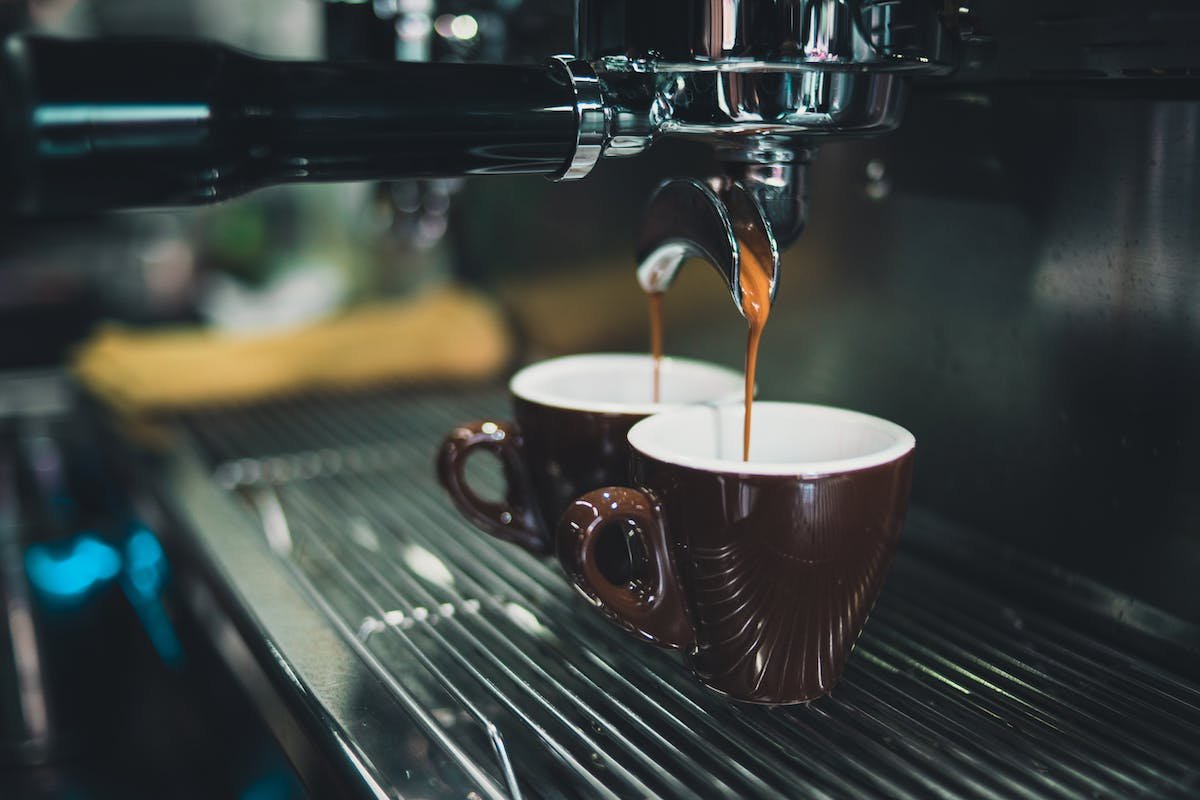 Máquina despejando café em duas xícaras - Metrópoles