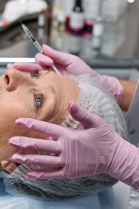 Mãos de médica segurando seringa de botox perto de rosto de paciente madura - Metrópoles